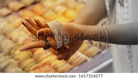 Hands of a woman trying to wear of bangles on her hand.Selective focus with copy space for text. Royalty-Free Stock Photo #1657316077