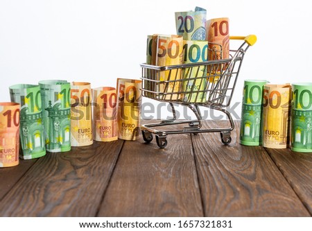 A shopping cart with money against a blue background
