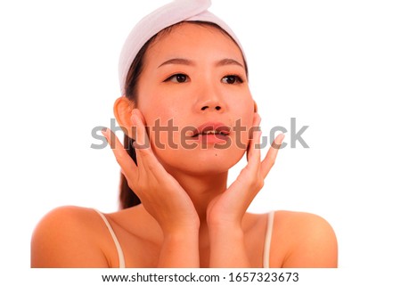 isolated portrait young beautiful and happy Asian Korean woman applying skincare wrinkle prevention treatment or aging beauty product on her face in makeup cosmetic and healthy lifestyle
