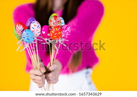 Easter holiday concept,Close up of Happy smile Asian Young woman wearing bunny ears hand holding colorful Easter eggs Skewers In isolated on Yellow blank copy space studio background.