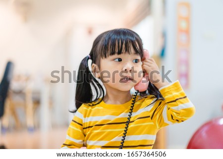 3 years old little asian girl holding vintage telephone talking and listening to her dad or father. Asian child girl call delivery food service in the morning.Children and vintage technology concept.