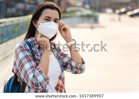 Asian woman wearing N95 mask to protect pollution PM2.5 and virus. COVID-19 Coronavirus and Air pollution pm2.5 concept. Royalty-Free Stock Photo #1657389907