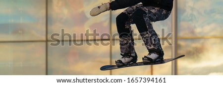 Young great skateboarder performs a trick on a city sportsground in winter. Young man jumps over an obstacles. Extreme sport is very popular among youth.