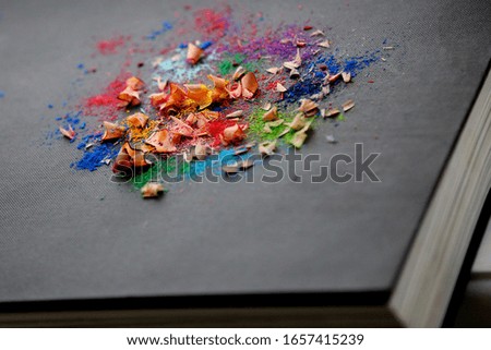 Colorful pencil's shavings are on the black fabric book's cover texture background close up taken with copy space around 