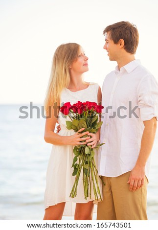 Young Couple in Love, Man giving beautiful woman bouquet of red roses, Romantic Date