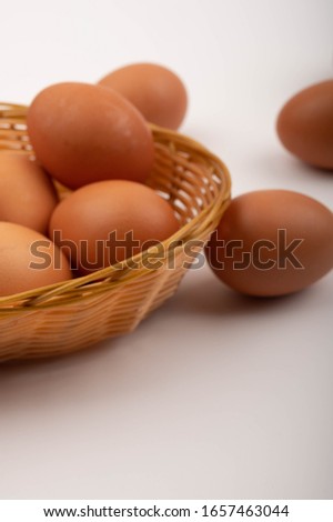 Chicken eggs in a wicker basket and scattered on a white background. Close up.