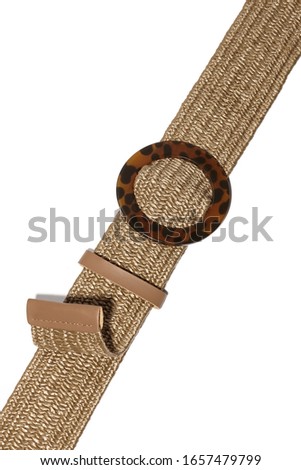 Cropped shot of a beige raffia belt with a round brown spotted buckle, a beige leather loop and a leather termination. The belt without holes is isolated on the white background.