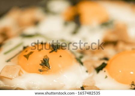 Fried eggs with slices of sausage and ham. Fried eggs sprinkled with parsley in a hot pan. Cooking Fried Eggs.
