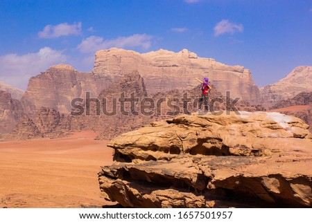 travel life style advertising concept photography of woman stay on top of high rock in the middle of Wadi Rum Jordan desert picturesque landscape environment majestic Middle East nature scenic view 