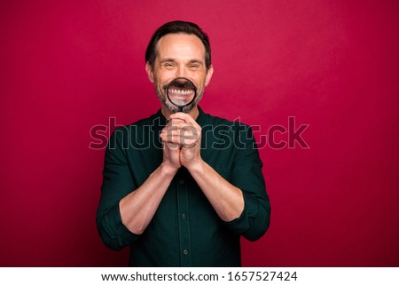 Photo of grimacing man enlarging his teeth with loupe showing his caries before going to dentist isolated vivid color background