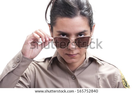 Pretty Hispanic female sheriff deputy dips sunglasses revealing bold penetrating eyes on white background