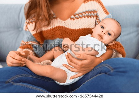 Young beautiful woman and her baby on the sofa at home. Newborn and mother relaxing and resting comfortable