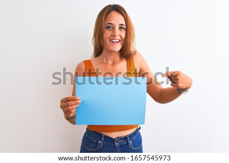 Young beautiful redhead woman holding banner over isolated background very happy pointing with hand and finger