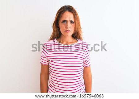 Young redhead woman wearing striped casual t-shirt stading over white isolated background depressed and worry for distress, crying angry and afraid. Sad expression.