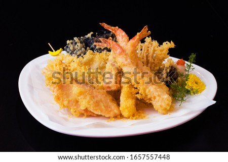 Japanese Cuisine - Tempura Shrimps shrimp in tempura with lemon slices and salad on a black background