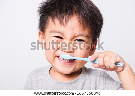 Closeup Asian face, cute little children boy hand holds toothbrush he brushing teeth myself on white background with copy space, health medical care