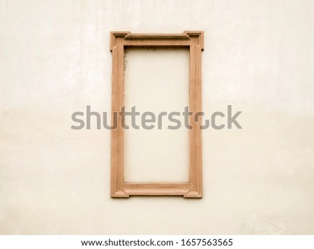 Part of a light beige wall with a brown frame.