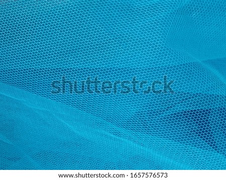 Beautiful blue background of transparent veil with several layers that create depth, airiness. Creative sky blue backdrop.