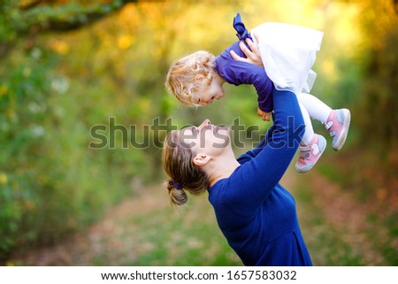 Lovely young mother having fun cute toddler daughter, family portrait together. Woman with beautiful baby girl in nature and forest. Mum with little child outdoors, hugging. Love, bonding.