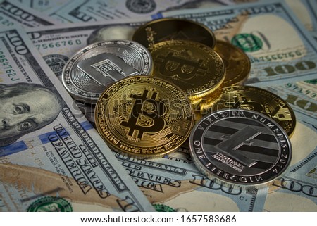 Gold and silver coins in the form of cryptocurrency on a pile of new-style hundred-dollar banknotes