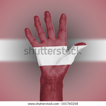Palm of a woman hand, painted with flag of Latvia