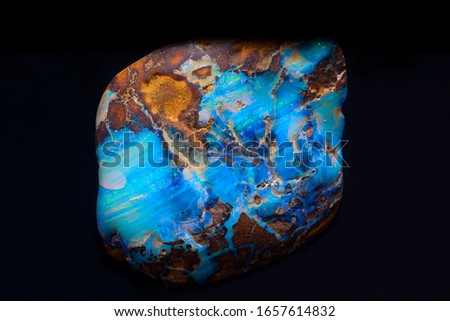 Beautiful piece of boulder opal from Queensland, Australia with a matrix of mainly pale blue opal on the natural stone background displayed on black.
