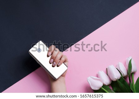 Congratulation card with mobile phone in woman's hand and spring white tulips flower on a duotone diagonal background.
