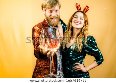 Happy couple holding a big glass of champagne. Man and woman very happy in a special day. Love concept. Yellow background. - Image