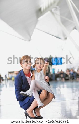 Young attractive airport staff talking to cute little girl in airport