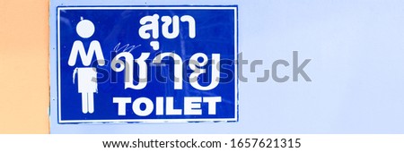 Toilet signs for man or toilets. Written in Thai and English alphabet. Pink background. Selective focus
