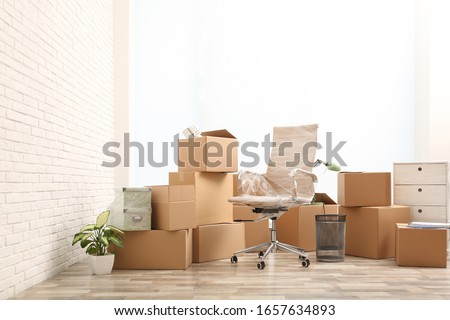 Moving boxes and stuff near white brick wall in room
