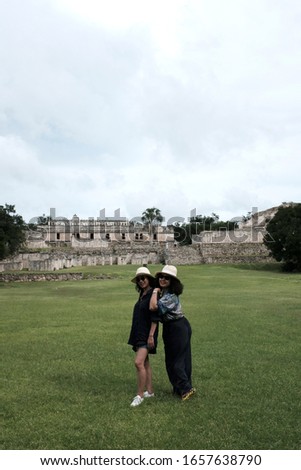 Asian female tourists posing for a picture in front of the old ruin in Kabah, a Maya archaeological site in the Puuc region of western Yucatan, south of Mérida.