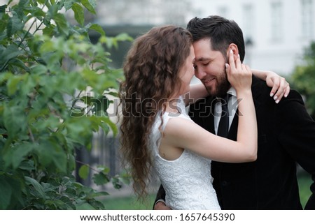Beautiful wedding couple of newlyweds - red-haired young bride in a white dress and a bearded groom in a black suit. Amazing smiling wedding couple. Pretty bride and stylish groom.