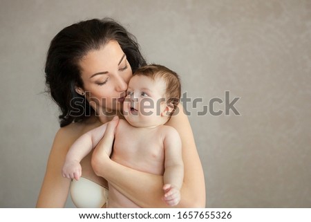 Happy family at home. Mother and baby daughter hugging and kissing. Loving mom carying of her little baby. 