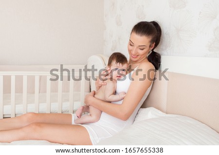 Happy family at home. Mother and baby daughter hugging and kissing. Loving mom carying of her little baby. 