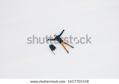 Young man lying on the white snow. Drone aerial view of snowy mountains in Kronplatz, Italy. It is a mountain of the Dolomites in South Tyrol, with a summit elevation of 2,275 metres