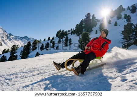 Young man speeding with vintage sledding on snow high mountain - Happy man having fun in white week vacation - Travel, winter sport, holiday concept - Focus on her face. Praxmar and in the Sellrain Va