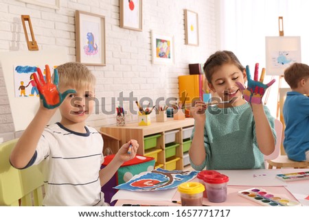 Cute little children with painted palms in room