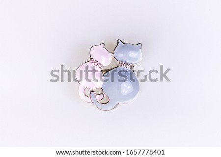 Shiny silver brooch in the shape of two hugging cats