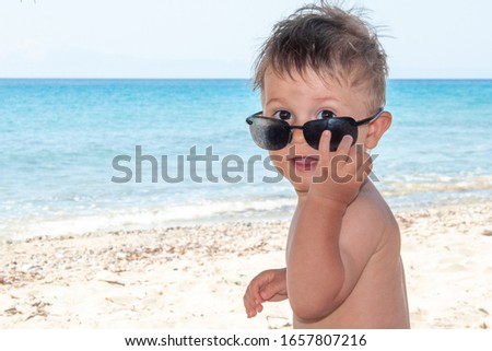  Kid play with sunglasses at the beach 
