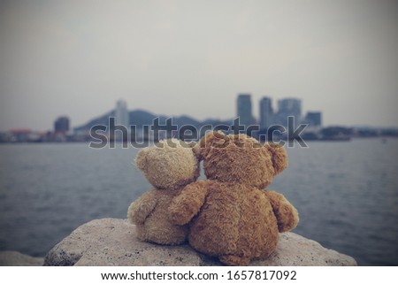 Two brown teddy bears so cute sitting on the rock looking to the city. Concept love, Valentine's day. Picture style old retro vintage.