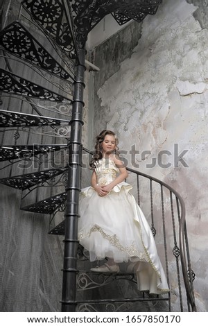 girl in a white elegant Victorian dress on a spiral staircase
