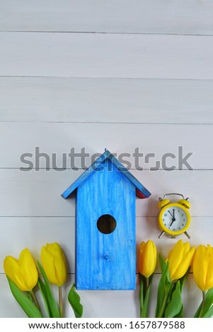 yellow tulips and a bright blue birdhouse on a pink background. picture for packages.Spring mood. Spring card for Mother's Day, Women's Day. Template greeting card for Valentine's Day.copy space.