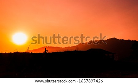 Silhouette of a man riding a bicycle on a hilltop at sunset. Male mountain biker cycling against a background of golden pink light at dusk.