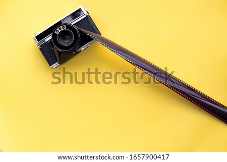 Black camera on the yellow background with film