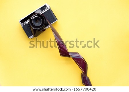 Black camera on the yellow background with film