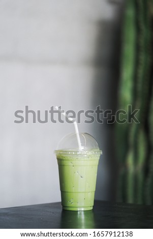 Japanese Matcha green tea ice latte on table.Iced mocha or matcha green tea latte in takeaway cup in cafe restaurant.Drinking Menu picture.