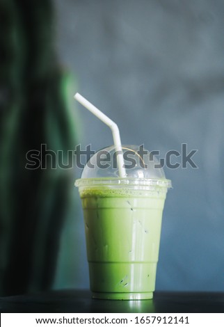 Japanese Matcha green tea ice latte on table.Iced mocha or matcha green tea latte in takeaway cup in cafe restaurant.Drinking Menu picture.