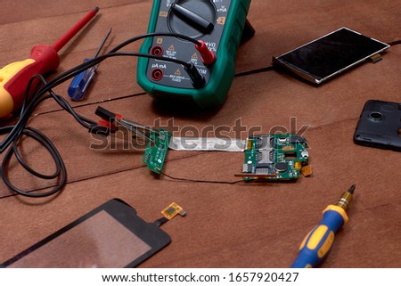 Motherboard of the mobile phone. Mobile phone repair shops. The screen and touchpad of the mobile phone. Electronics repair tool. double-sided tape. Multimeter.