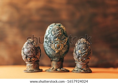 vinage Easter eggs decorated with papier-mache hand made, beautiful decorations on egg at stand, pictures on egg, look like stones eggs, jewellery, on wooden background.